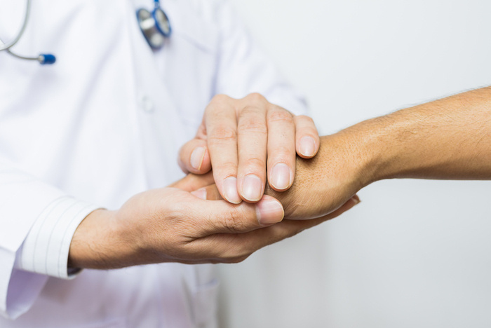 a physician is holding the hands of a patient. 