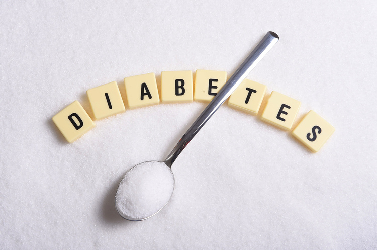 Diabetes spelt out in letter tiles with spoon of sugar laying across the top