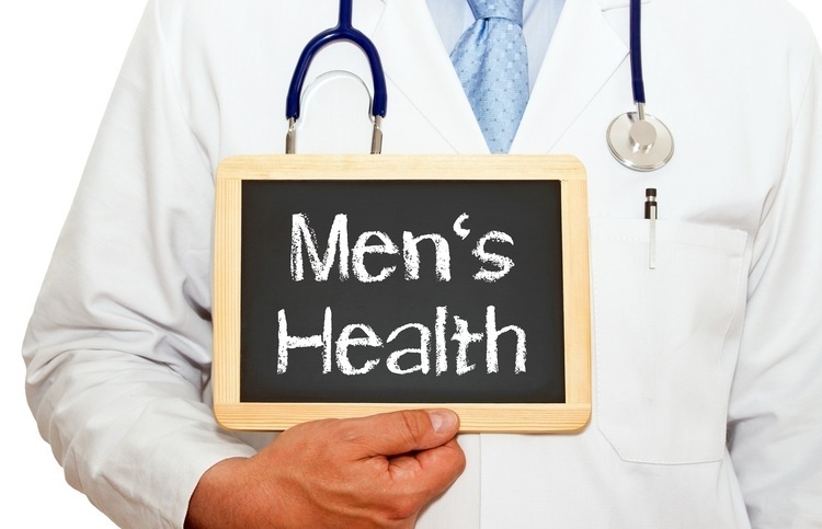 man in white coat, tie, and stethoscope holding sign that reads "Men's Health"
